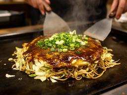 広島——鉄板の上で層になるお好み焼き、ソースの香ばしい湯気